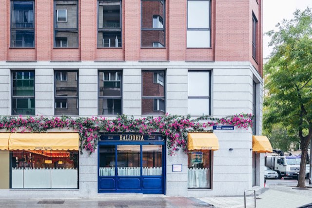 Baldoria corner facade with flowers and yellow awnings